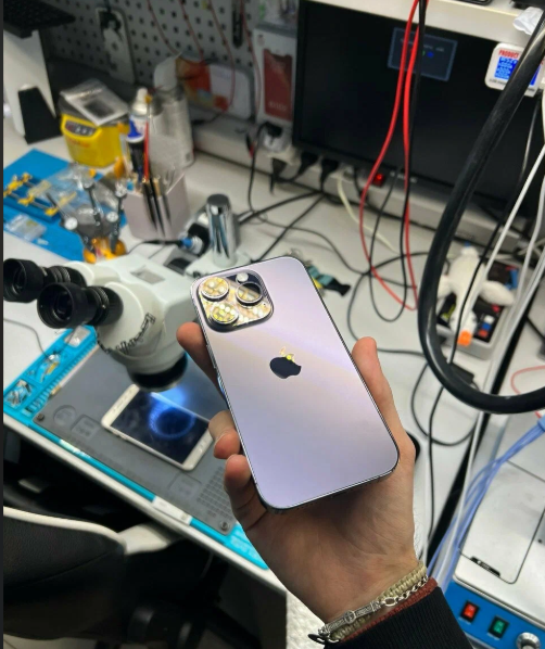 iPhone в руках мастера на фоне рабочего места